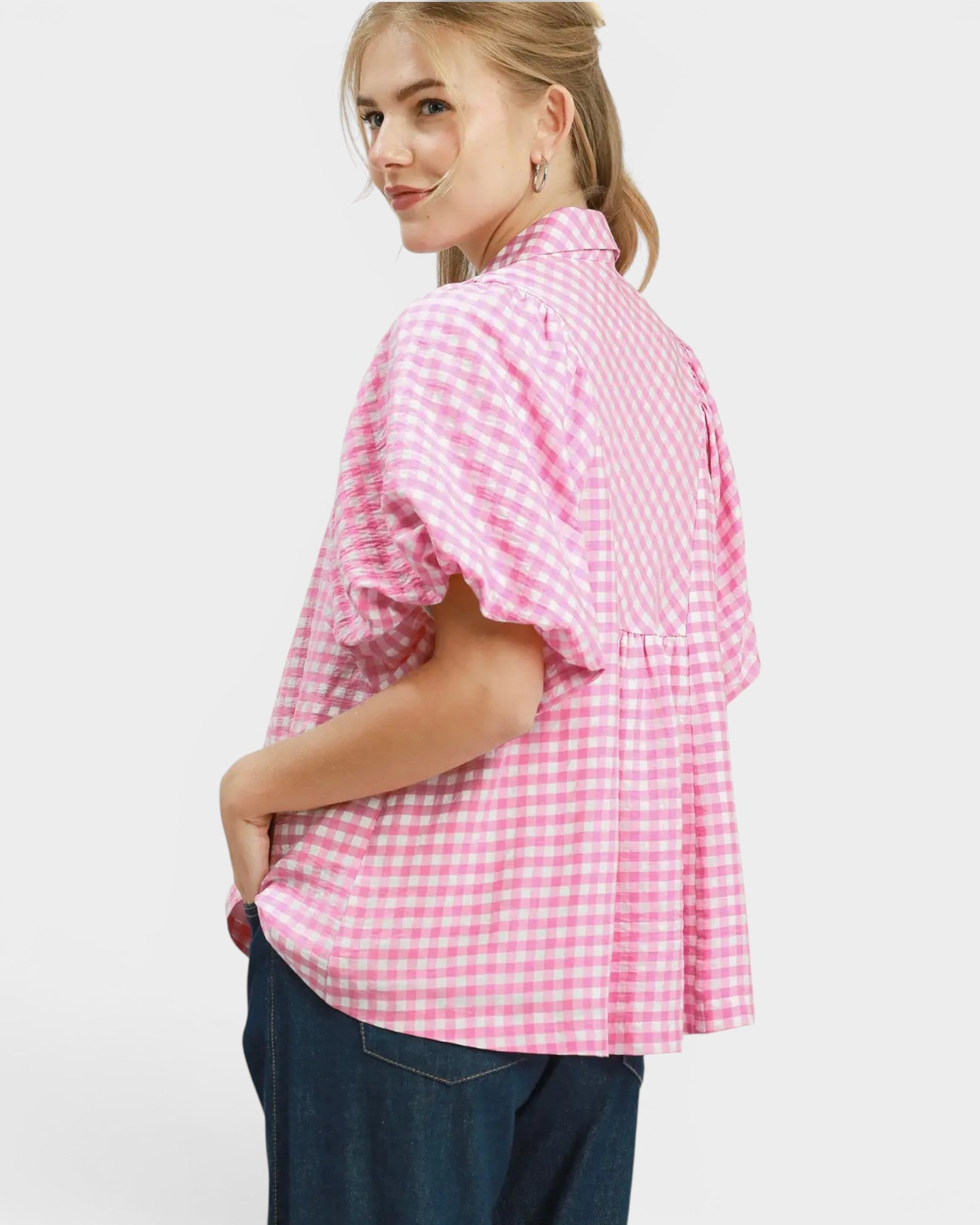 Woman wearing a pink and white checkered blouse on a white background
