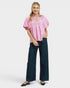 Woman wearing a pink checkered blouse and dark blue pants on a white background