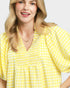 Woman wearing a yellow checkered blouse against a plain background
