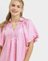 Woman wearing a pink checkered dress on a plain background