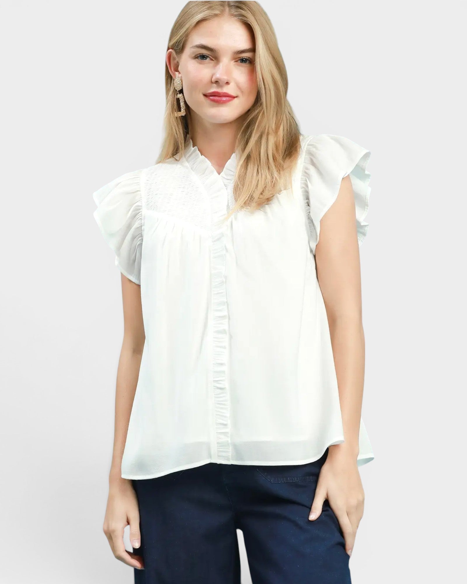 White blouse with ruffled sleeves worn by a person on a plain background