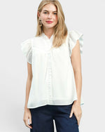 White blouse with ruffled sleeves worn by a person on a plain background