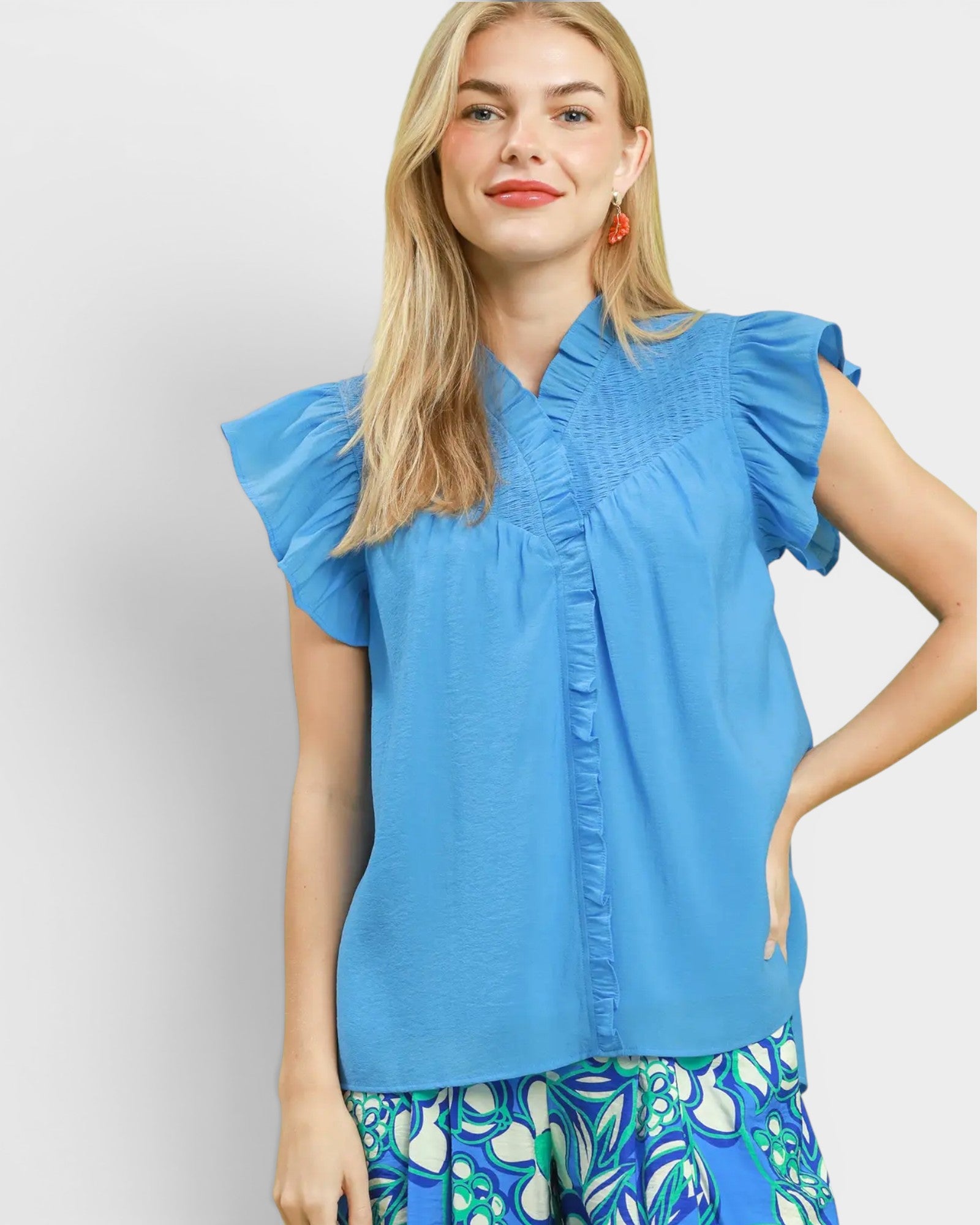 Woman wearing a blue blouse with ruffled sleeves on a light gray background