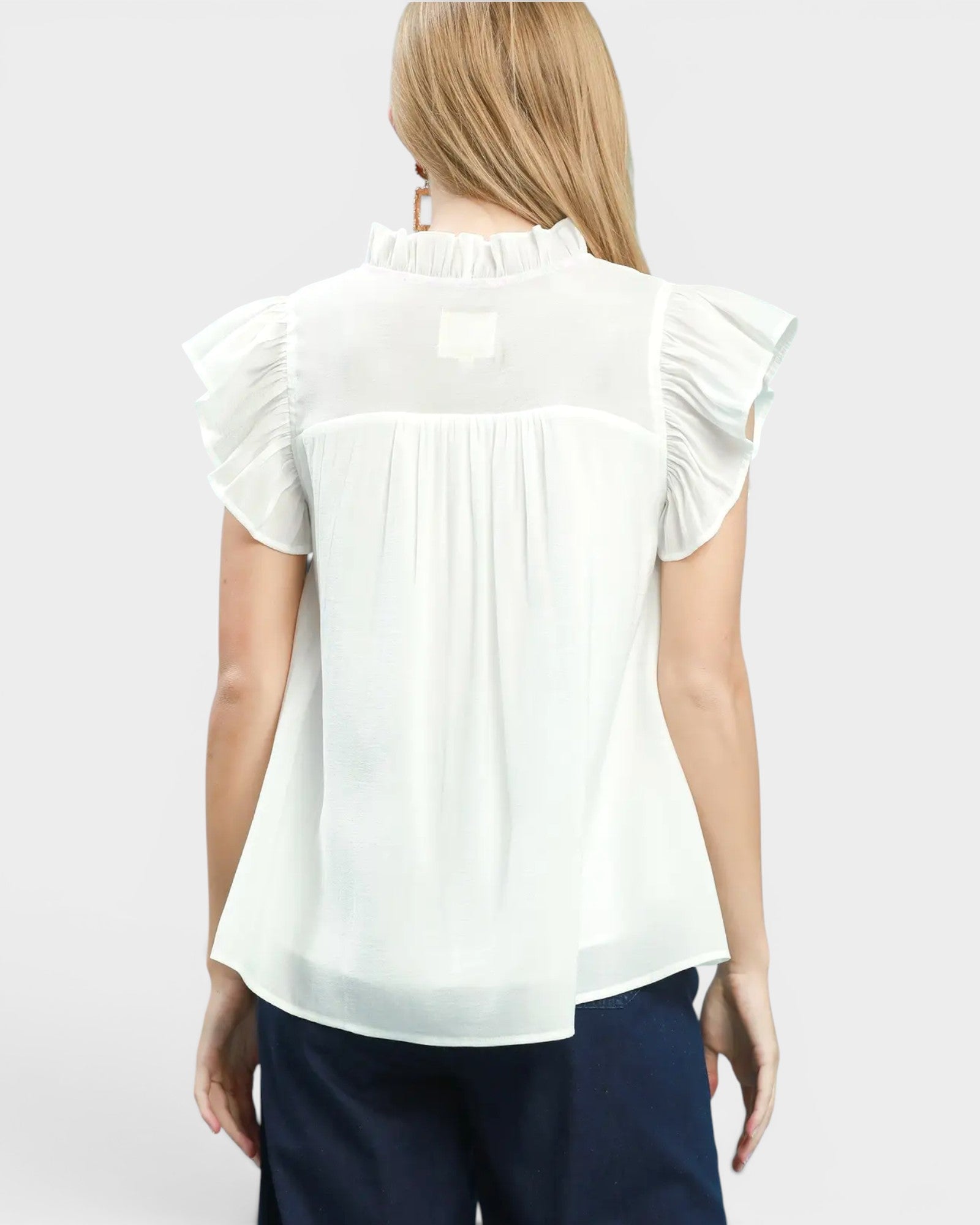 White blouse with ruffled sleeves worn by a person on a plain background