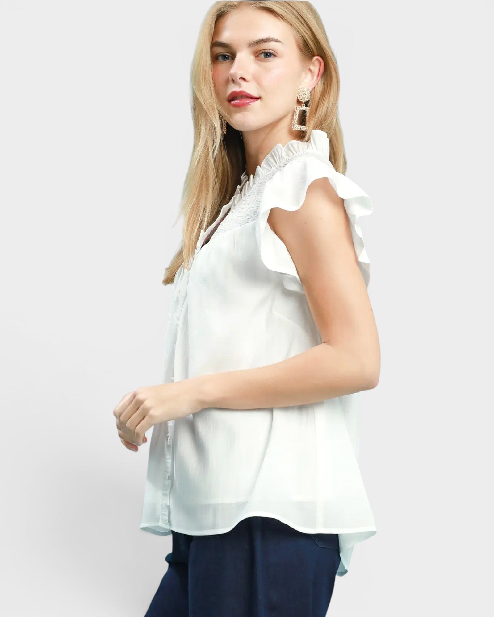 Woman wearing a white blouse with ruffled sleeves on a light gray background