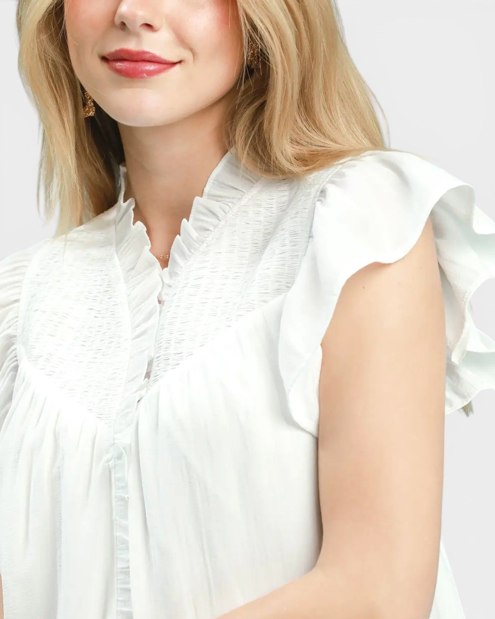 White blouse with ruffled sleeves worn by a person on a plain background