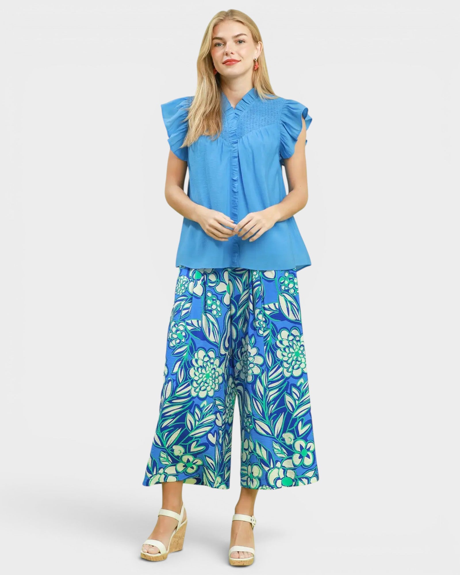 Woman wearing a blue top and floral pants on a white background