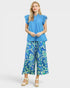 Woman wearing a blue top and floral pants on a white background