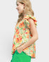 Woman wearing a colorful floral top with ruffled sleeves on a white background