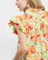 Woman wearing a colorful floral dress on a plain background