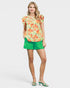Woman wearing a floral top and green shorts on a white background