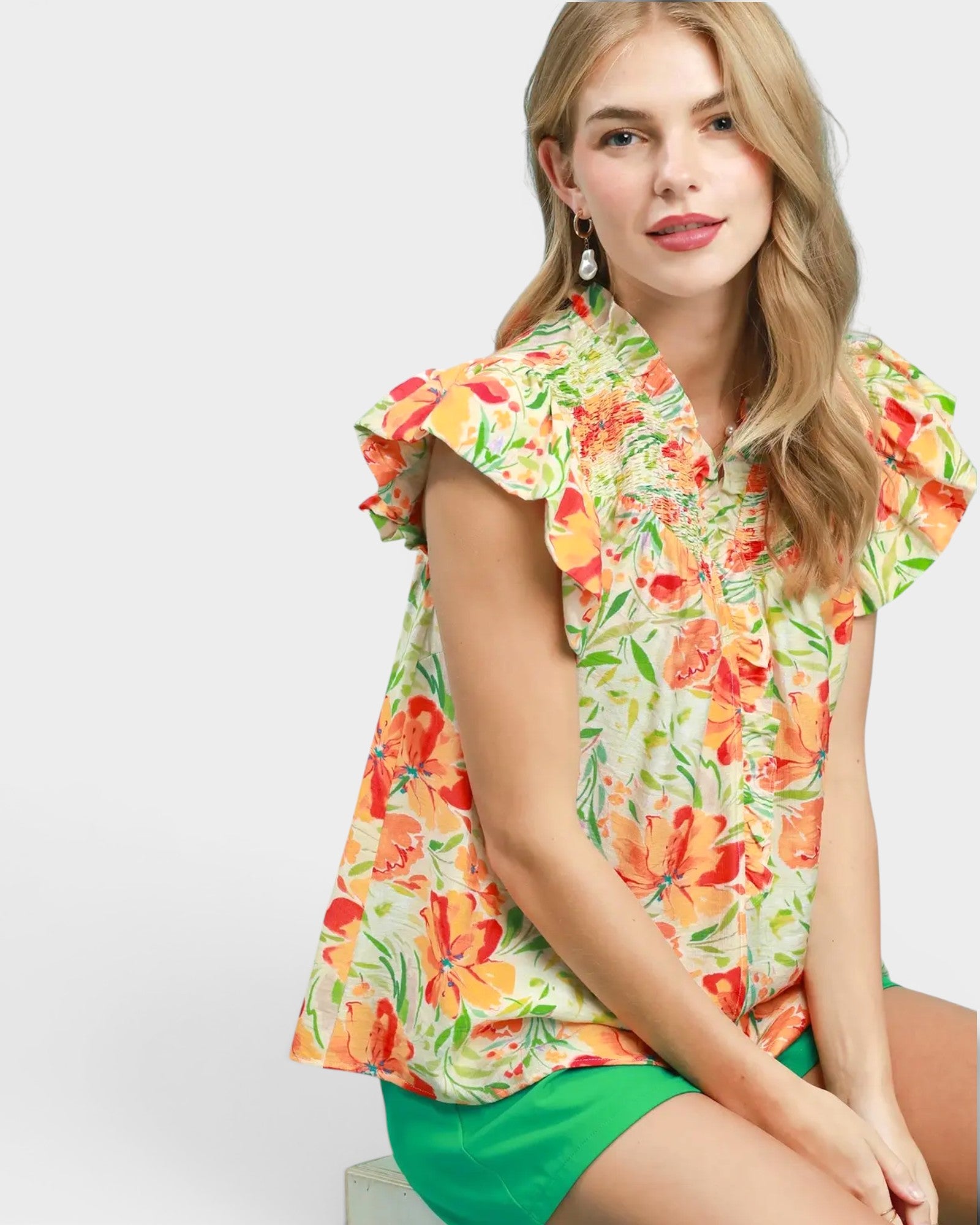 Woman wearing a colorful floral blouse with ruffled sleeves on a white background