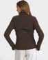 A woman shown from the back wearing a dark brown long-sleeve cropped jacket with a draped shoulder detail and white pants, against a light gray studio background.