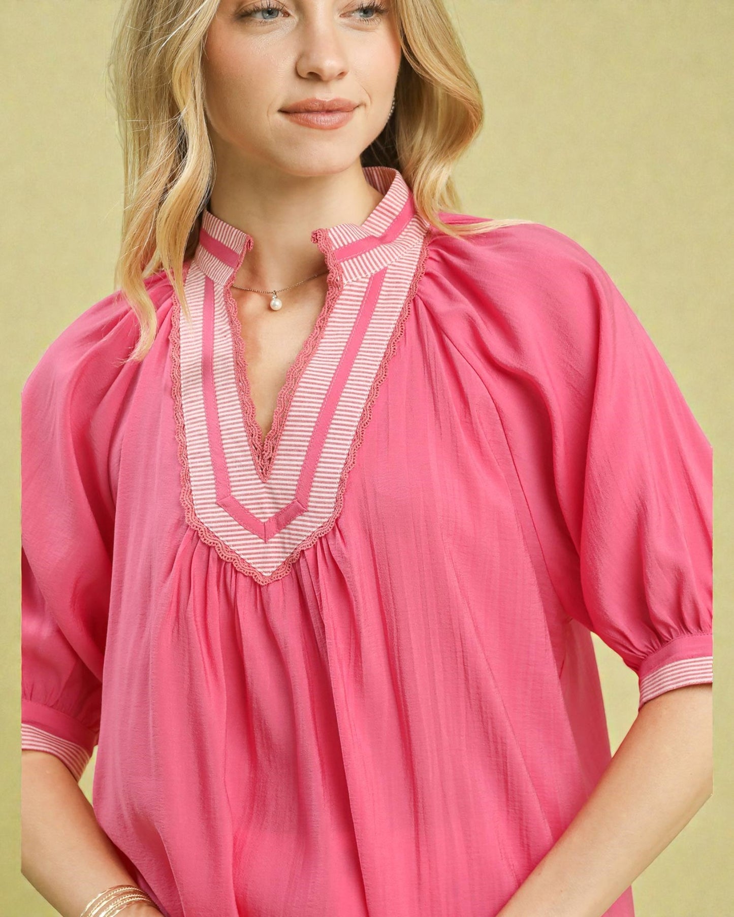 Woman wearing a pink blouse with white trim against a yellow background