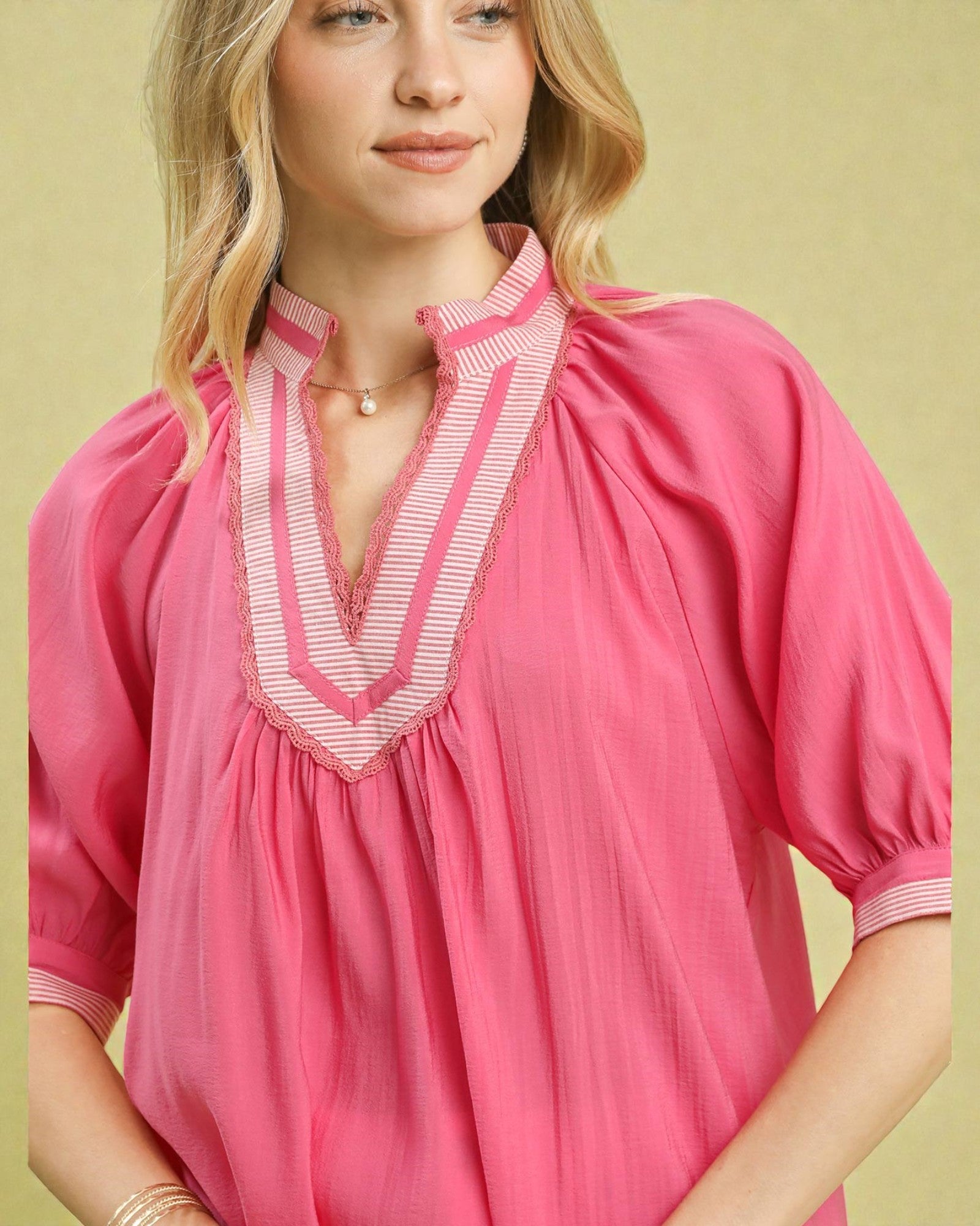 Woman wearing a pink blouse with white trim against a yellow background