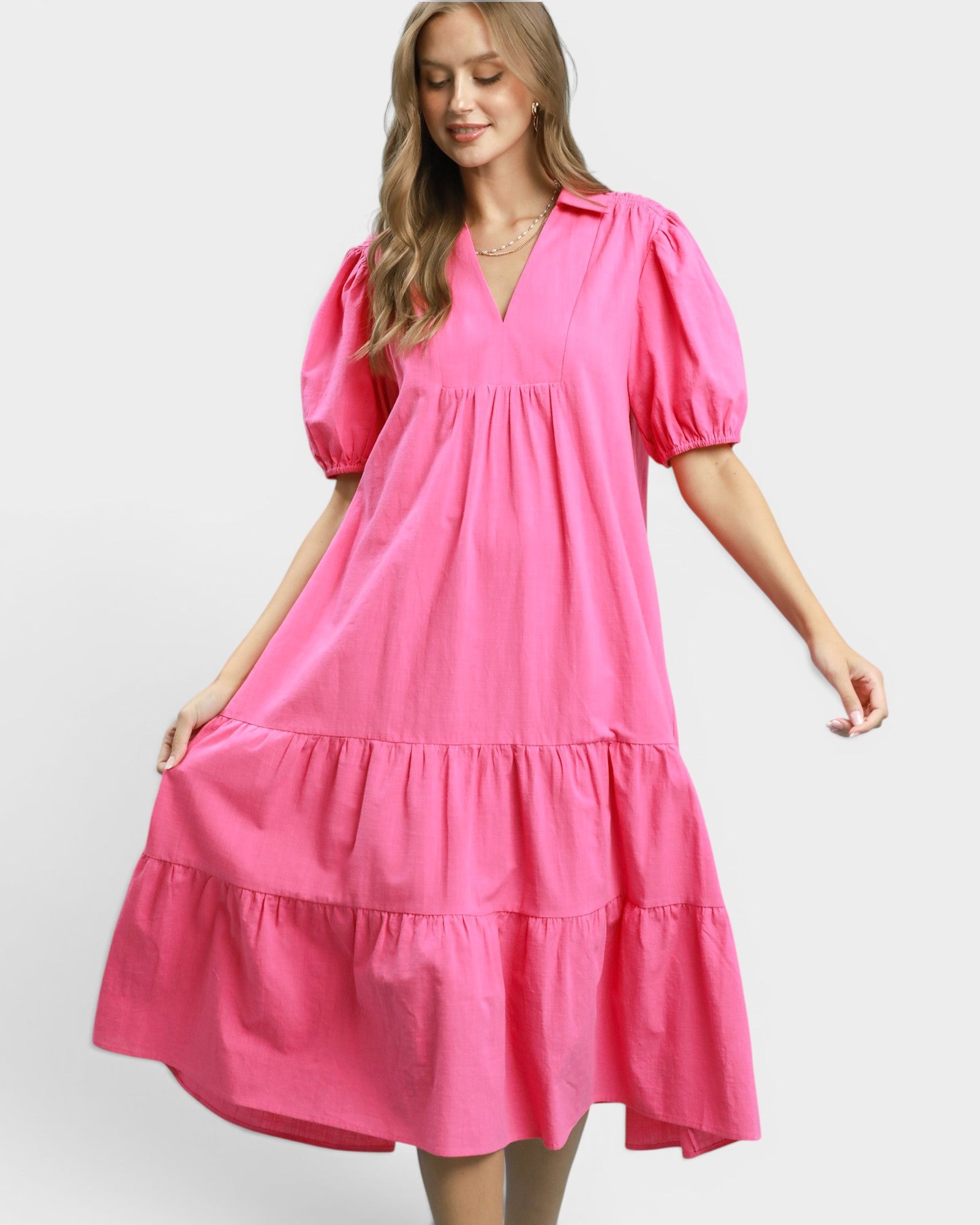 Woman wearing a bright pink dress with puff sleeves on a white background