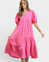 Woman wearing a bright pink dress with puff sleeves on a white background