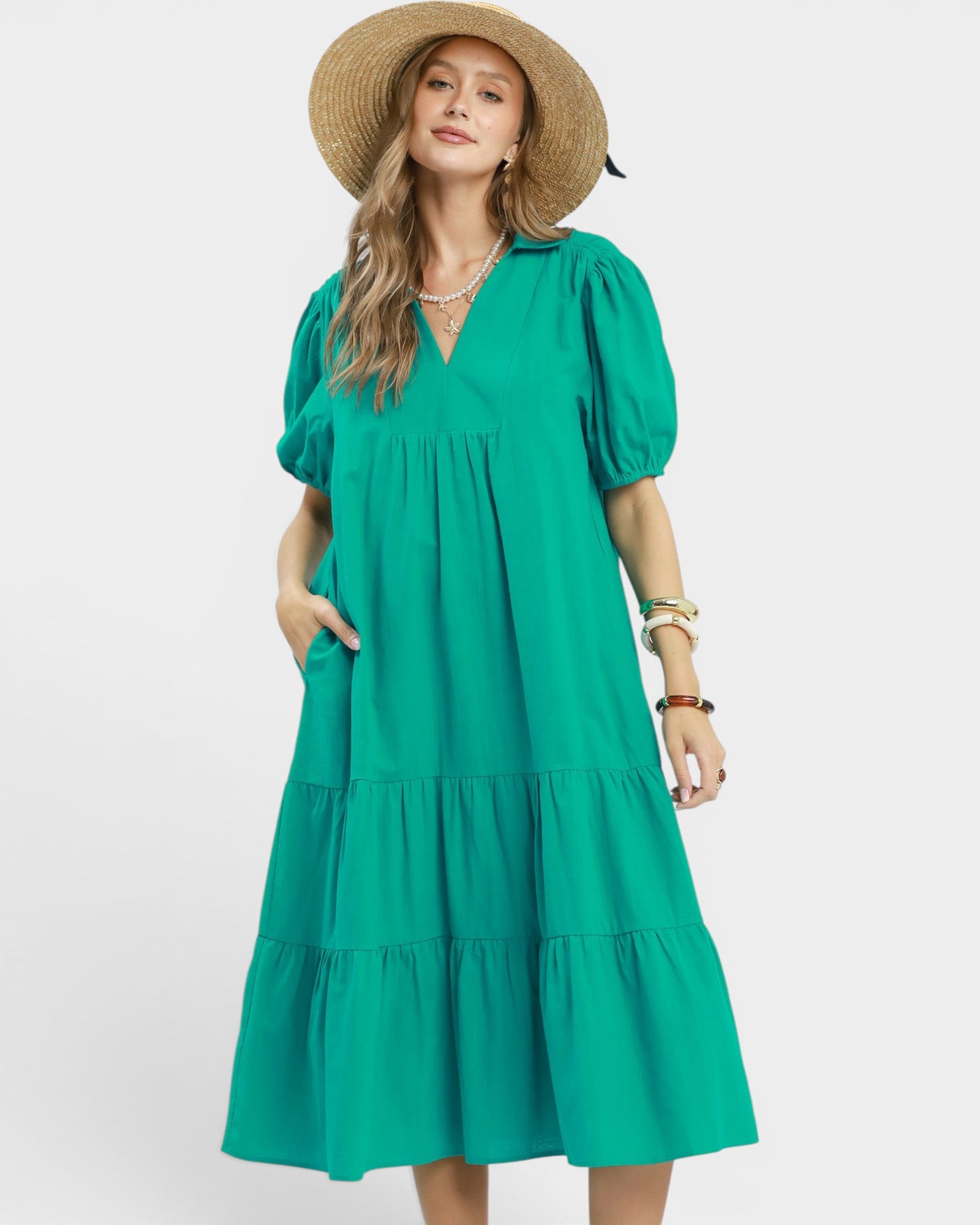 Woman wearing a green dress and straw hat on a white background