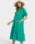 Woman wearing a green dress and straw hat on a white background