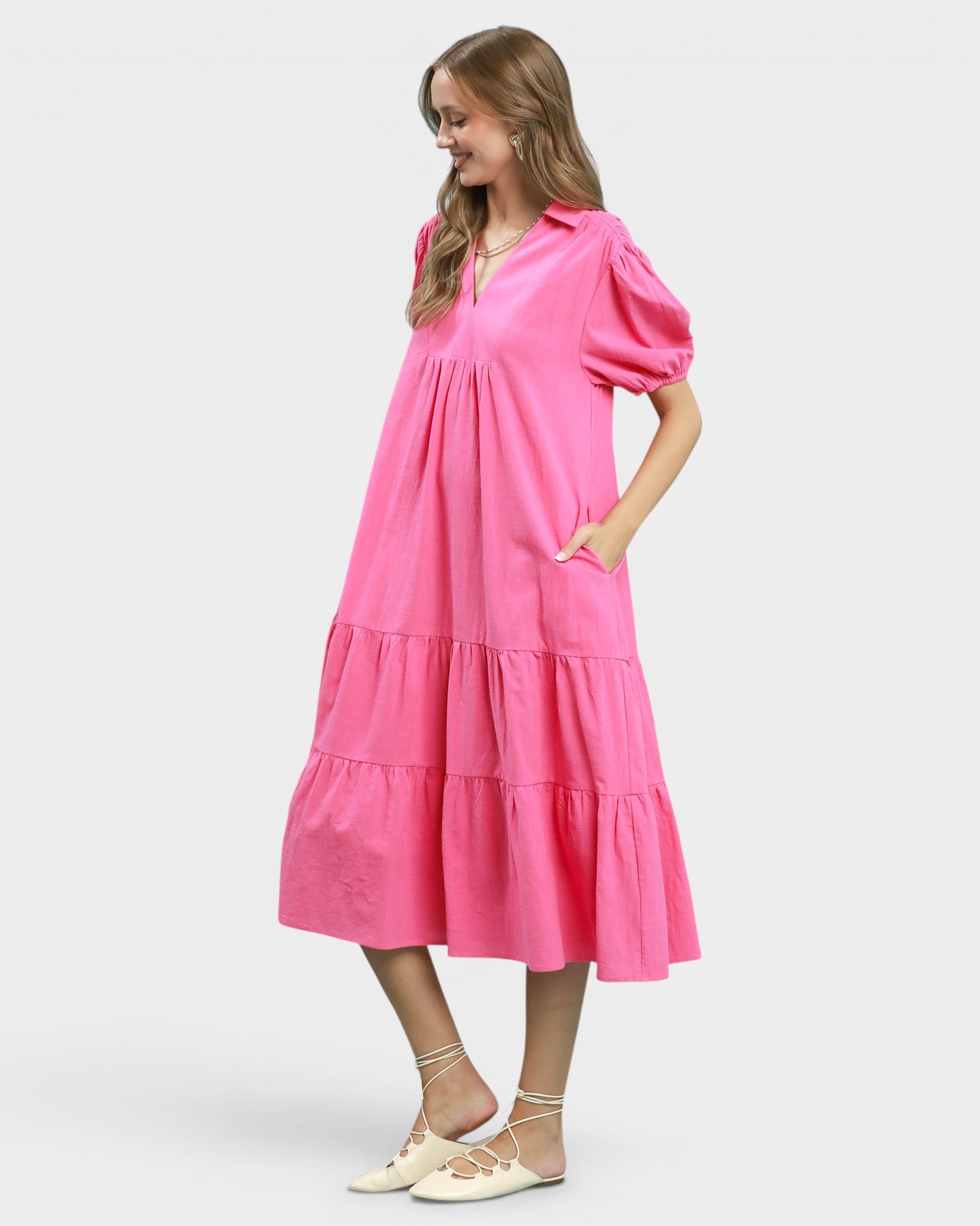 Woman wearing a pink dress with puff sleeves on a white background