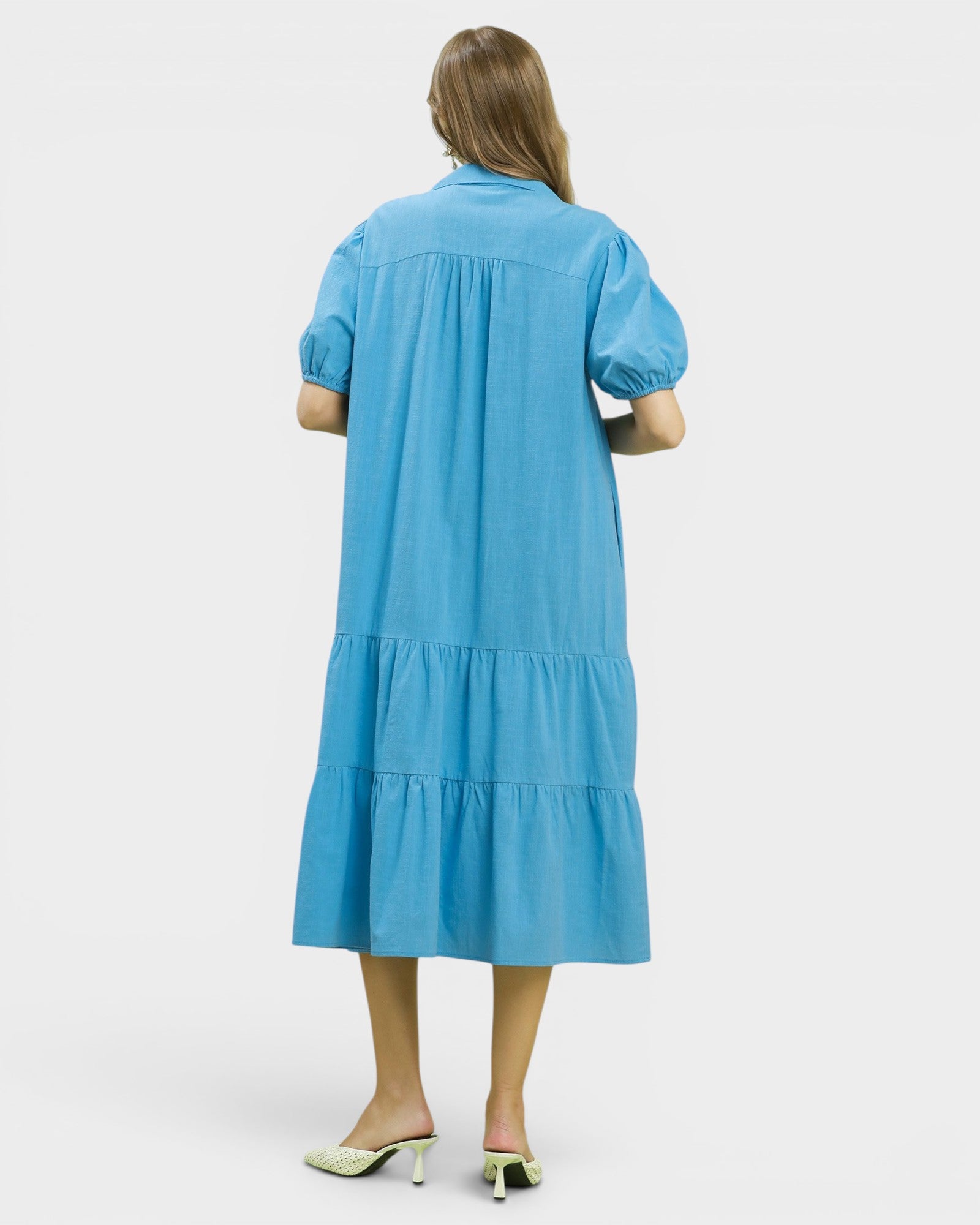Woman wearing a blue dress with puff sleeves on a white background