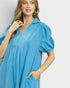 Woman wearing a blue dress with puff sleeves against a white background