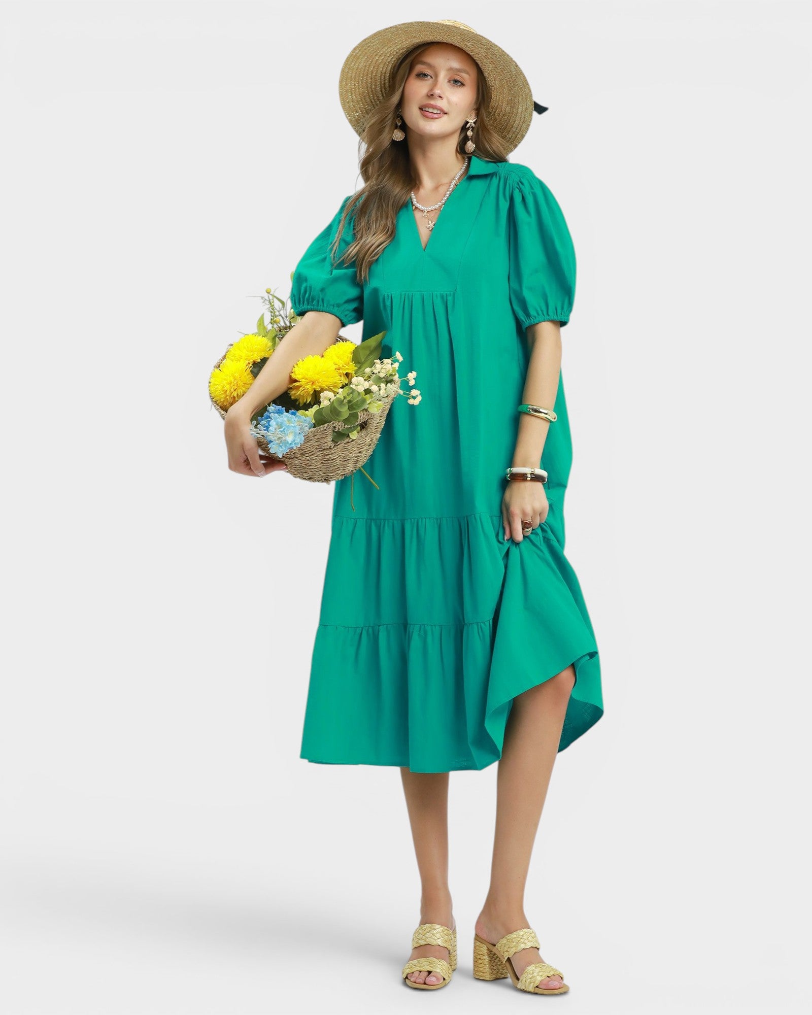 Woman in a green dress holding flowers against a white background