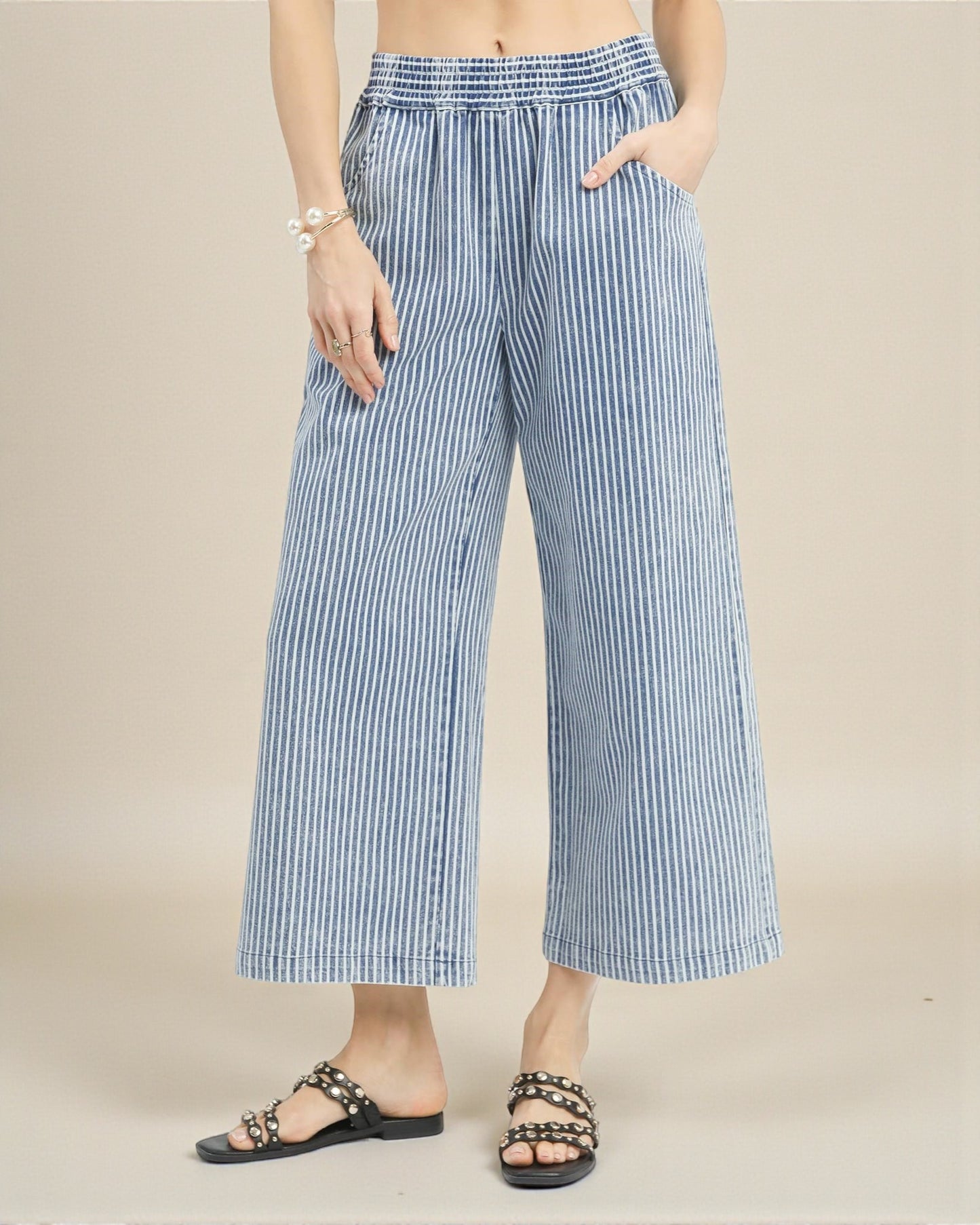 Blue and white striped wide-leg pants worn by a person on a beige background