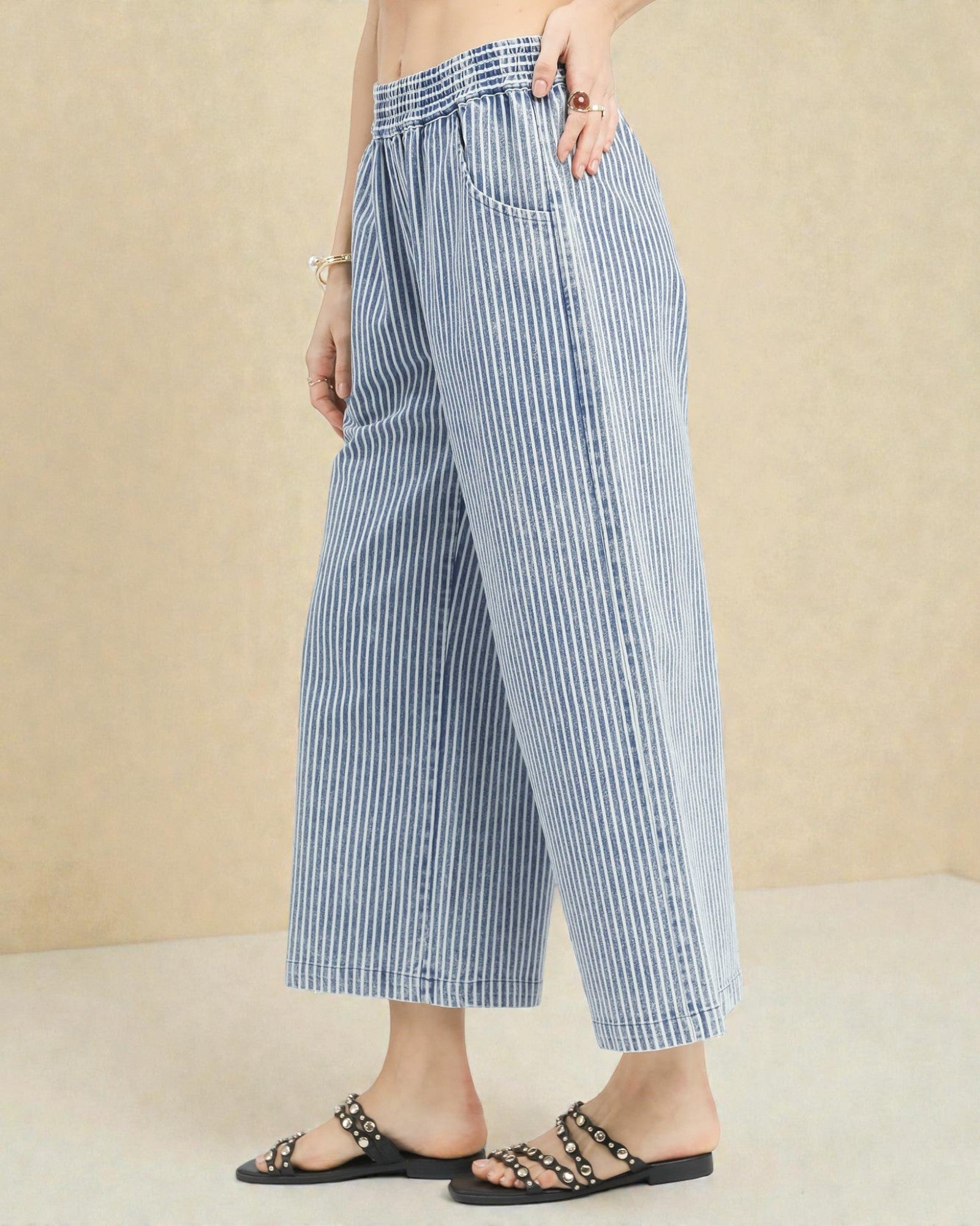 Person wearing blue and white striped wide-leg pants on a beige background