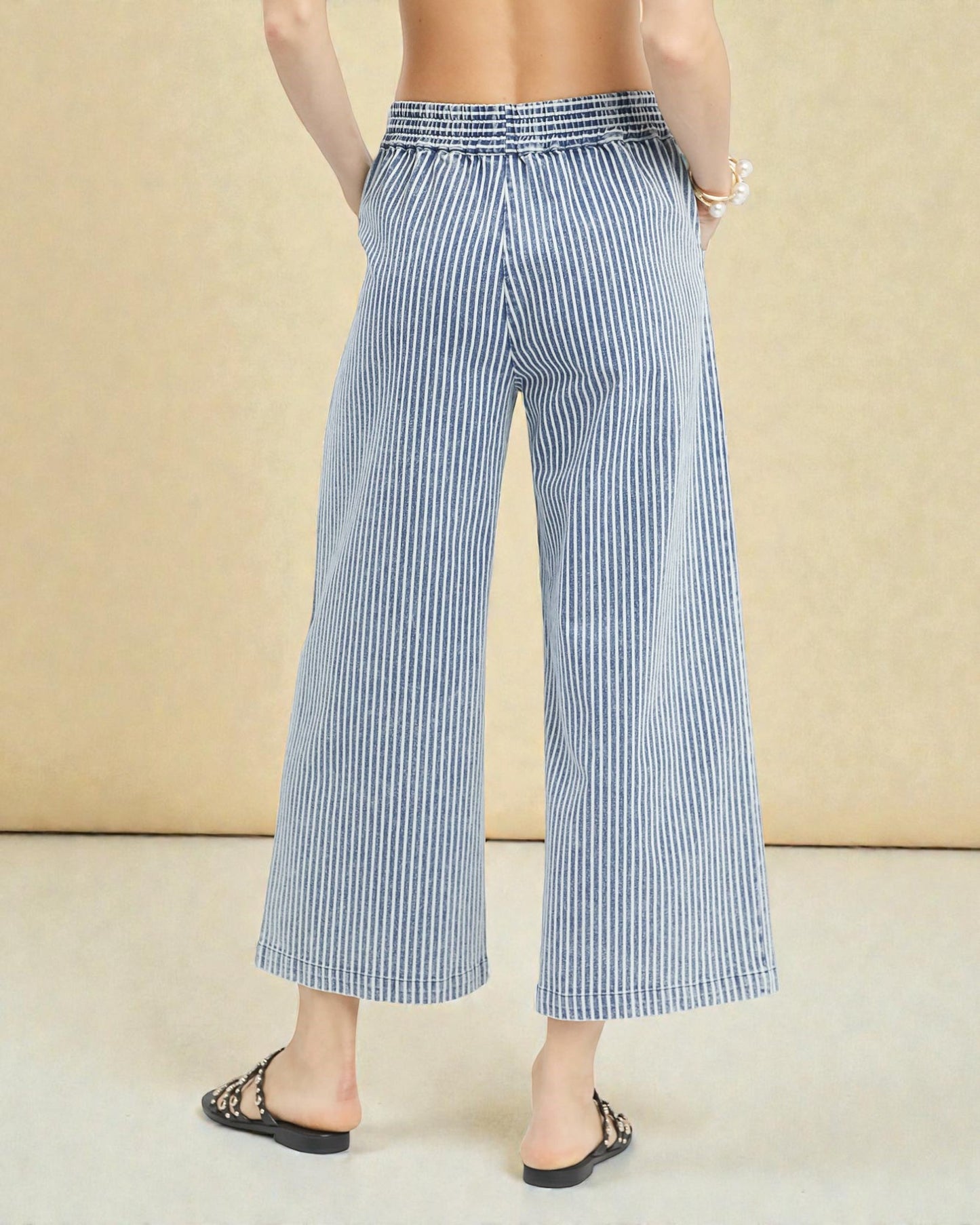 Blue and white striped pants worn by a person on a beige background