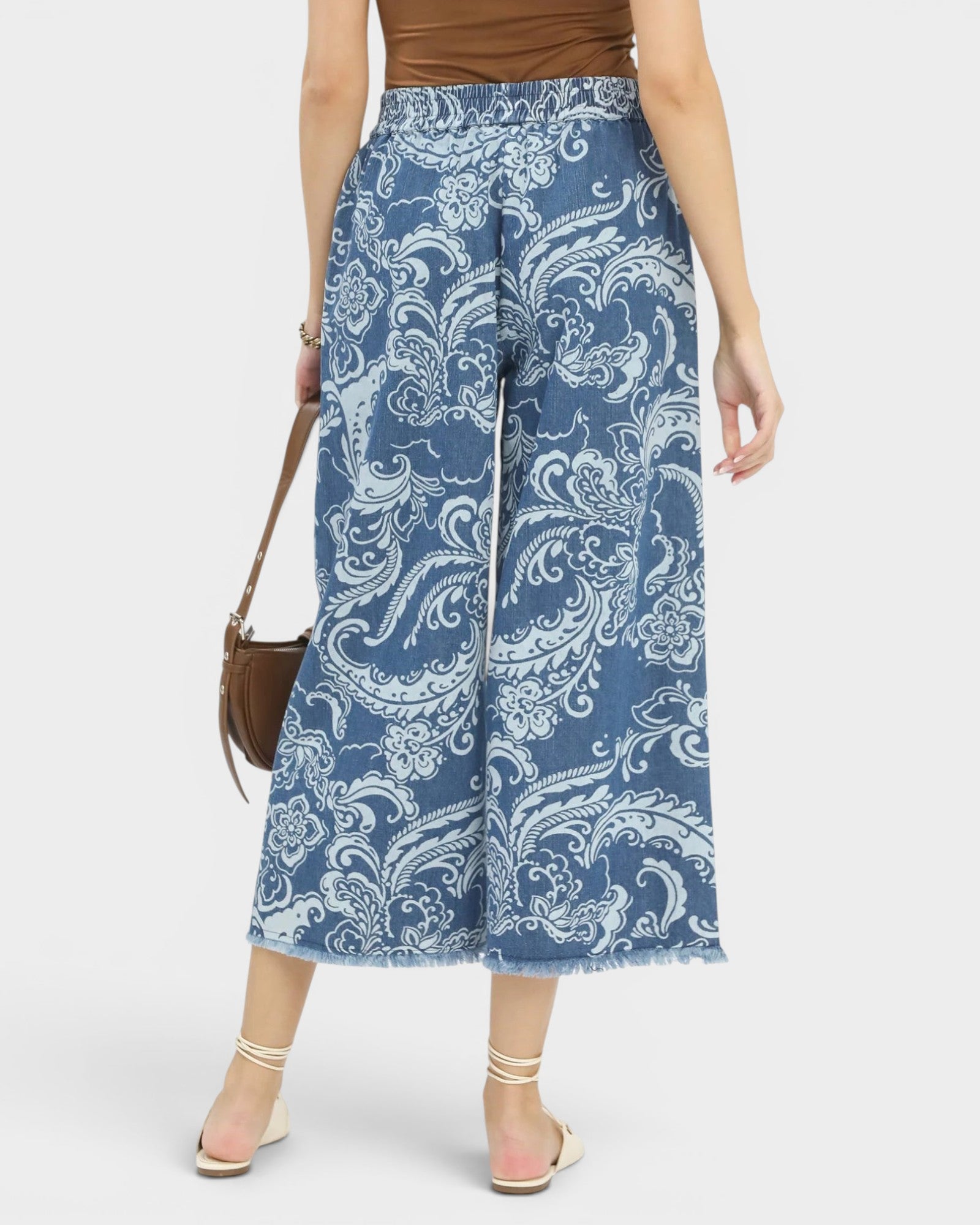 Woman wearing blue paisley patterned pants on a white background