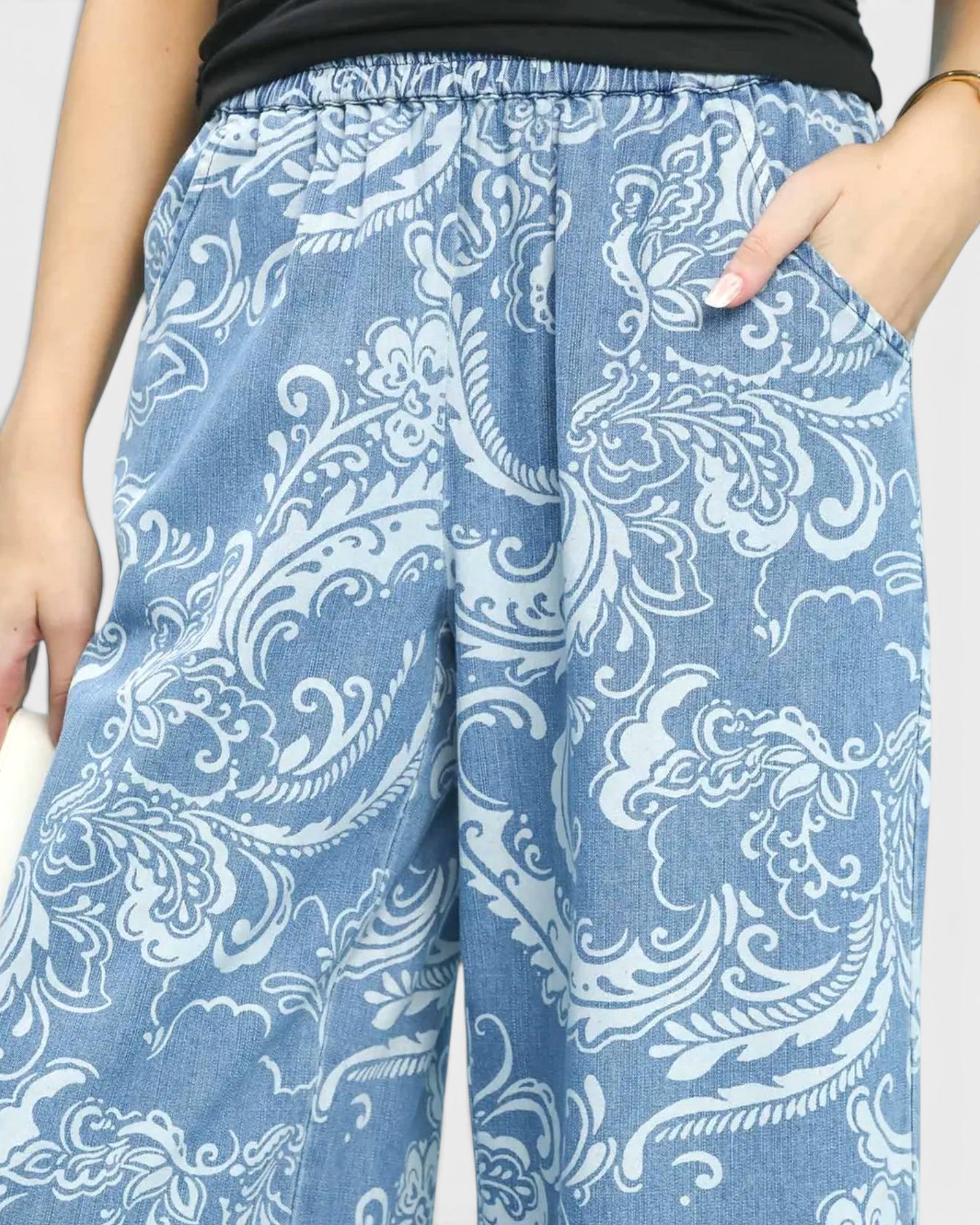 Blue pants with white floral pattern worn by a person on a plain background