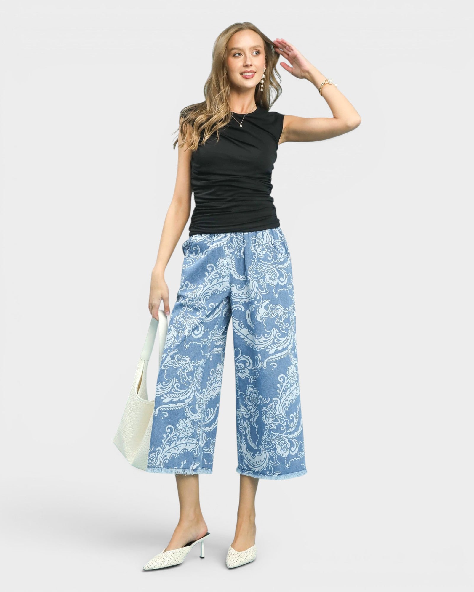 Woman wearing a black sleeveless top and blue patterned pants on a white background