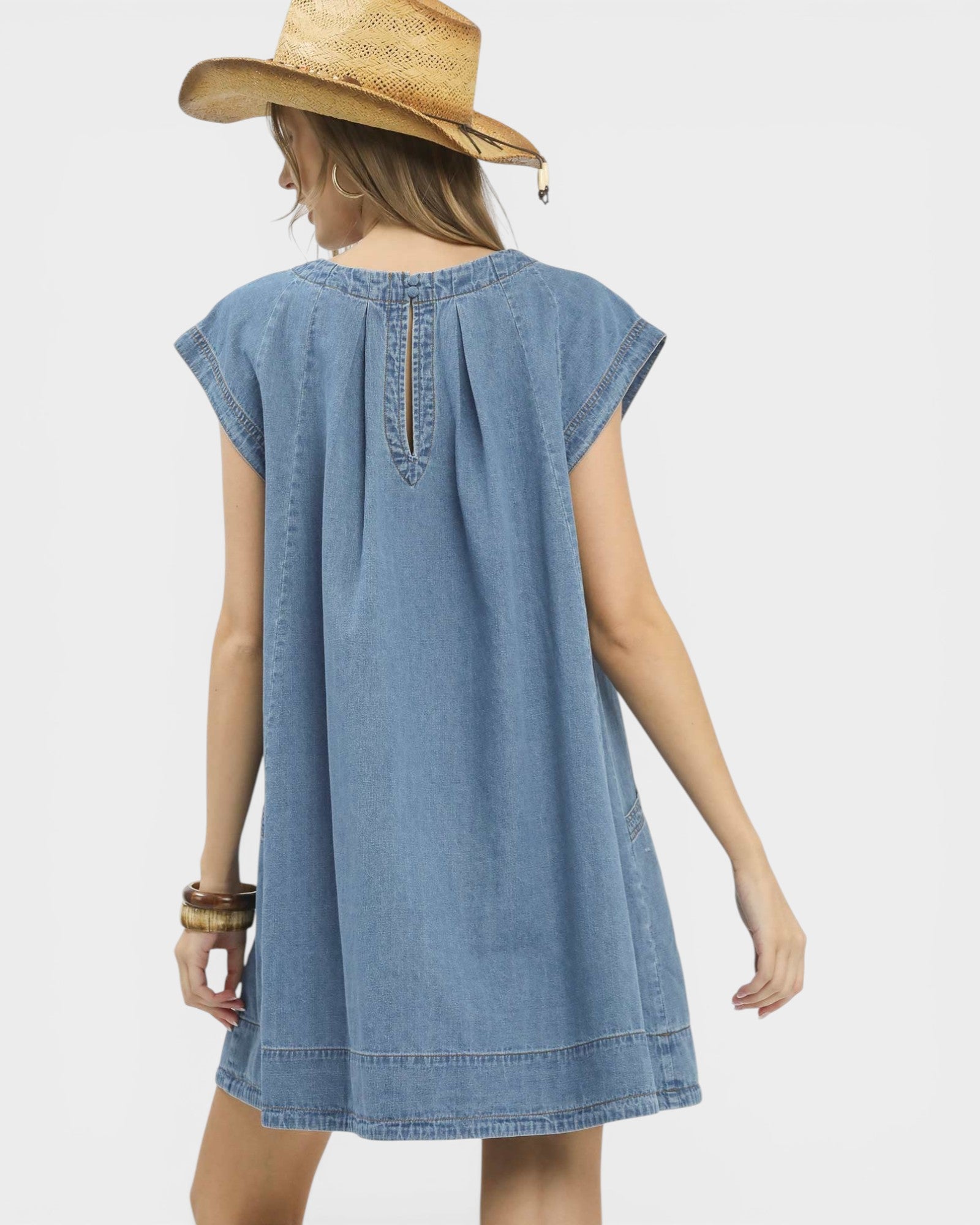 Woman wearing a blue denim dress and straw hat on a white background