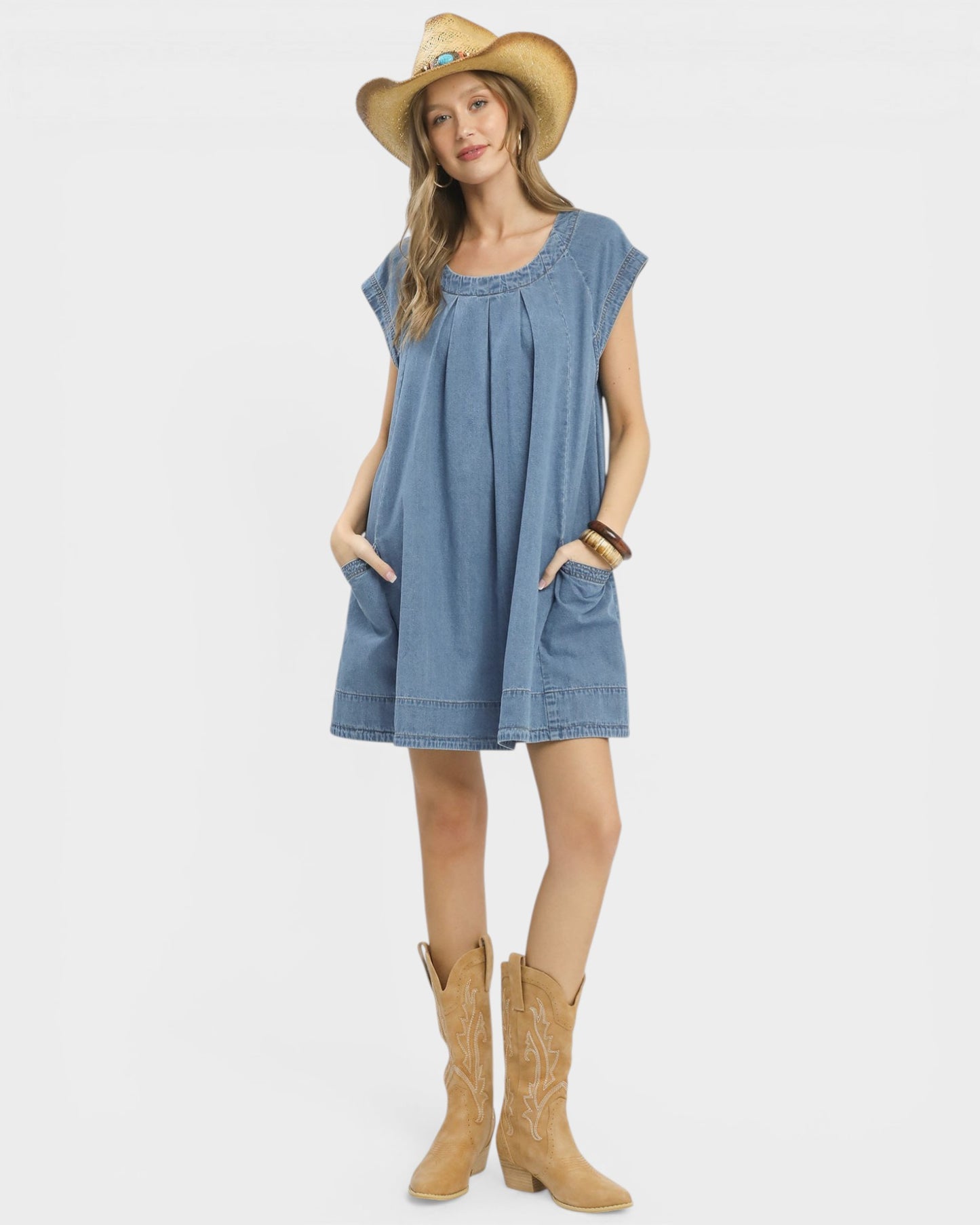 Woman wearing a blue dress, tan cowboy hat, and tan boots on a white background