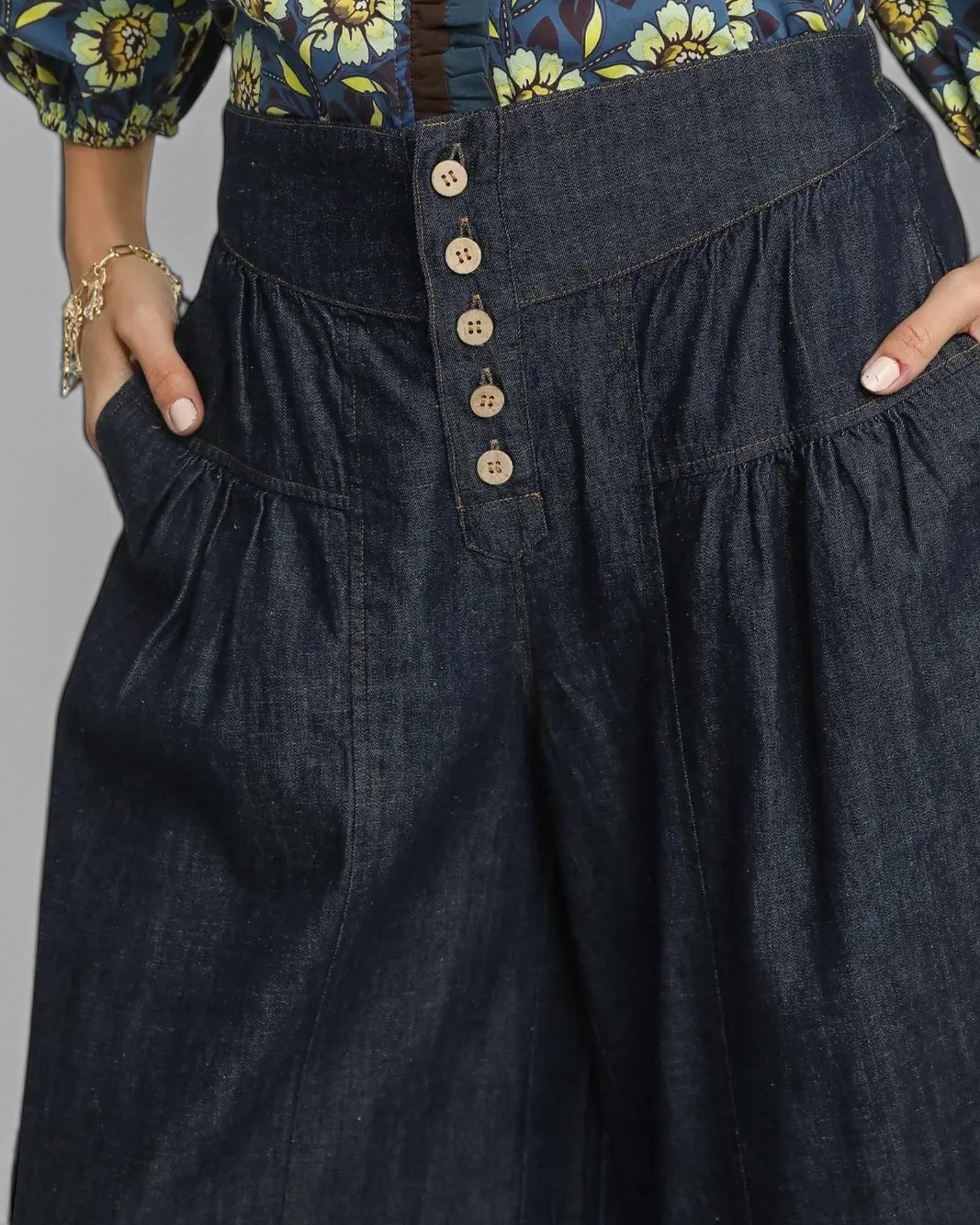 Dark denim pants with button details on a gray background