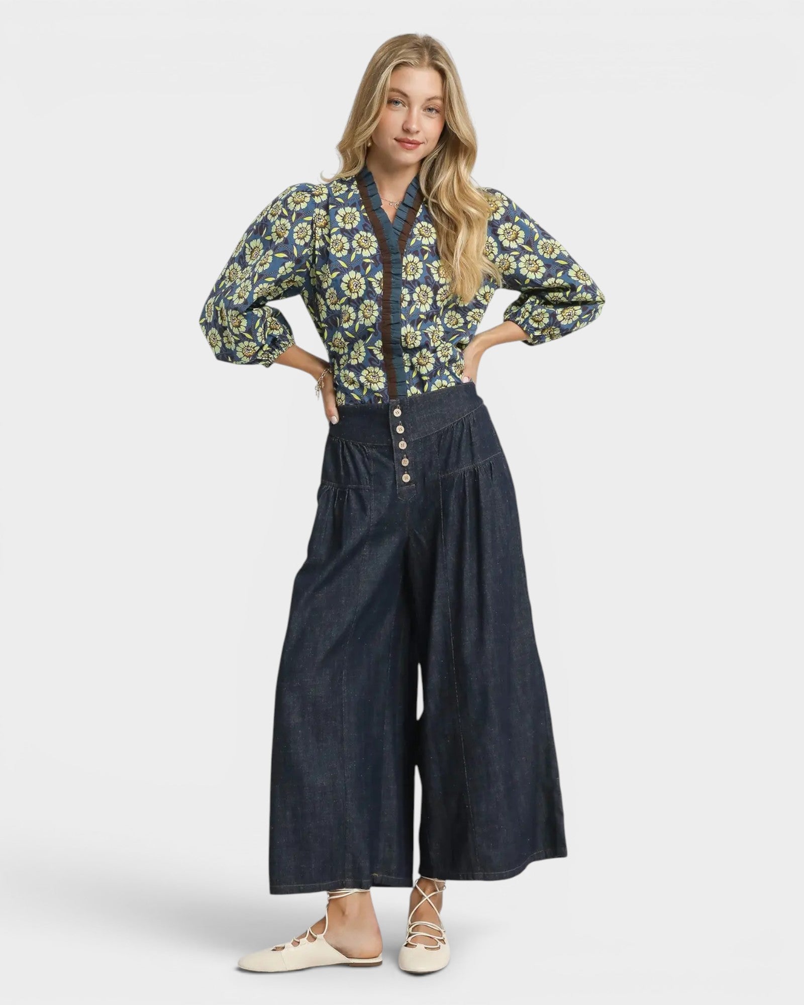 Woman wearing a floral blouse and wide-leg jeans on a white background