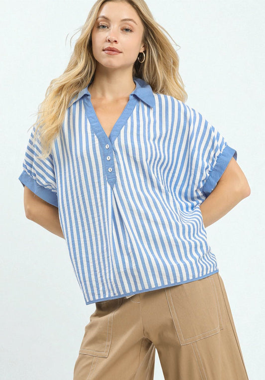 Woman wearing a blue and white striped shirt with beige pants on a light gray background