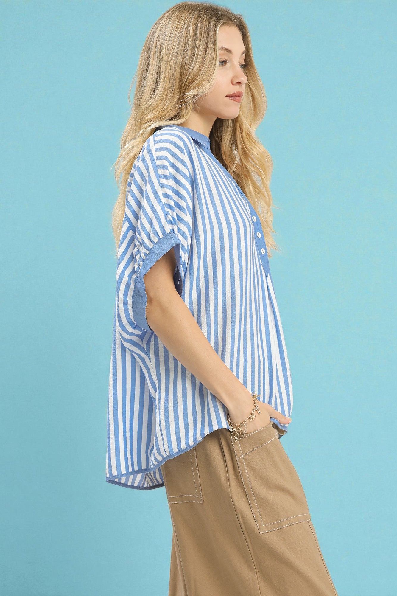 Woman wearing a blue and white striped shirt against a light blue background