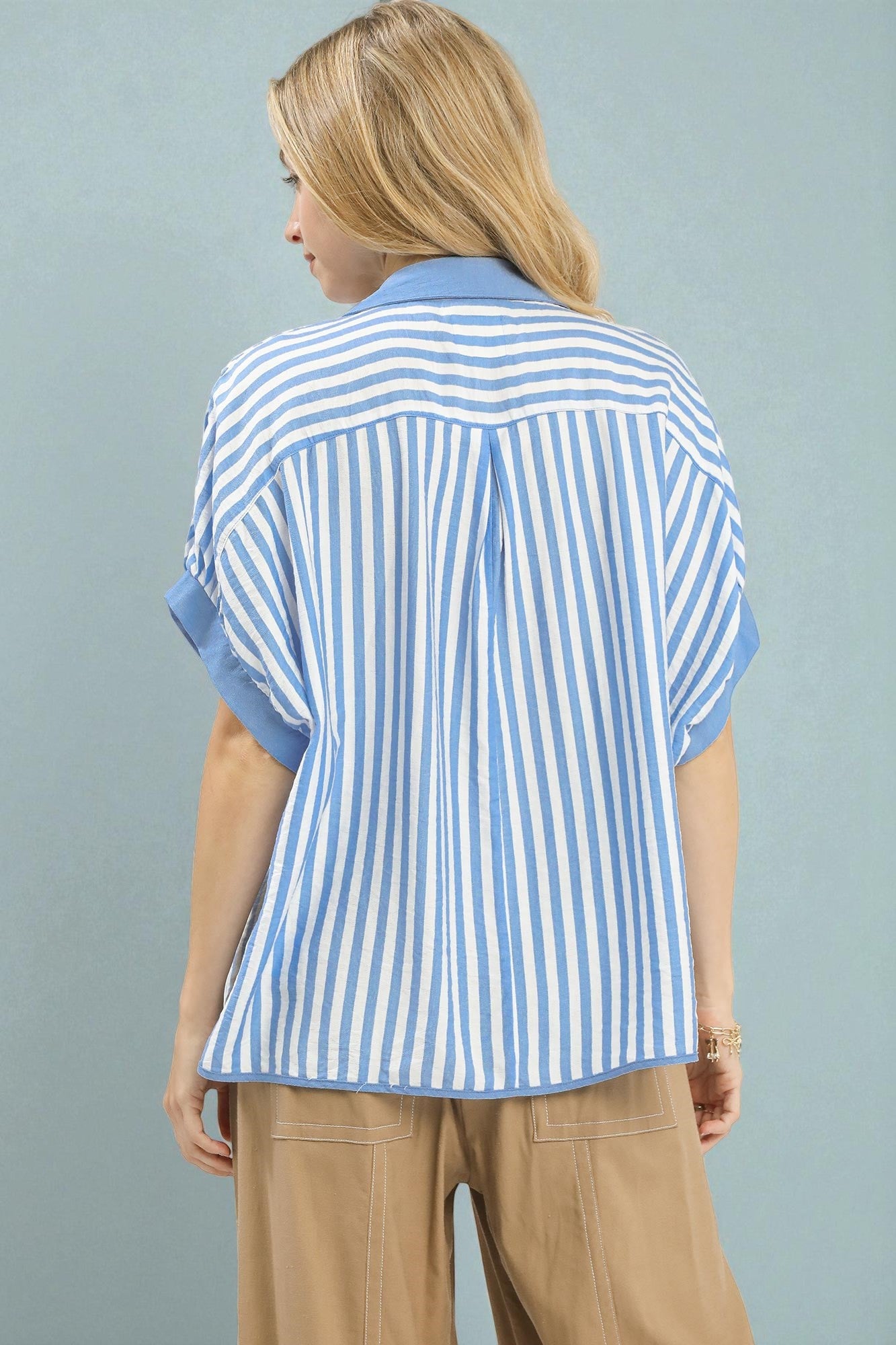 Woman wearing a blue and white striped shirt against a gray background