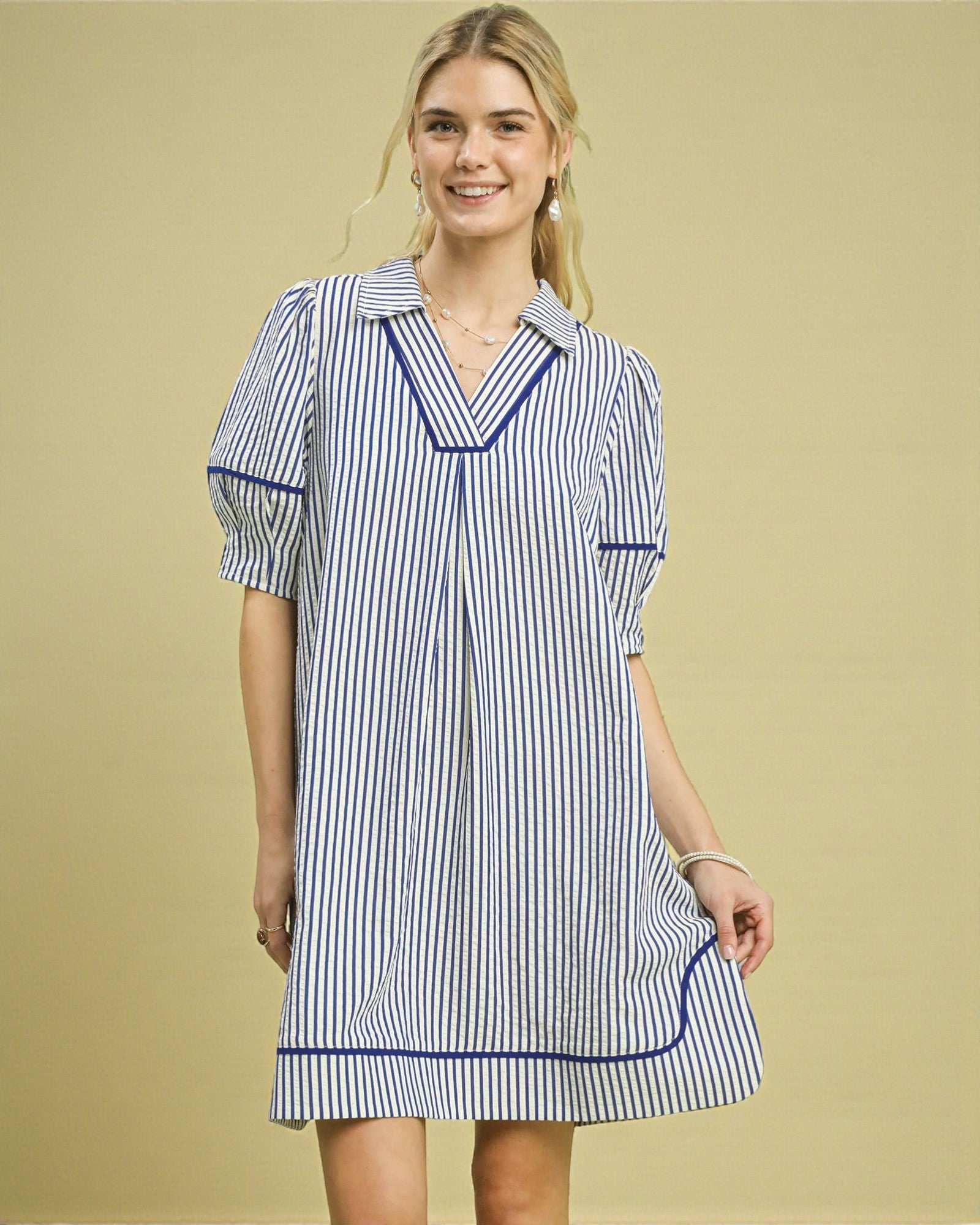 Woman wearing a blue and white striped dress against a beige background