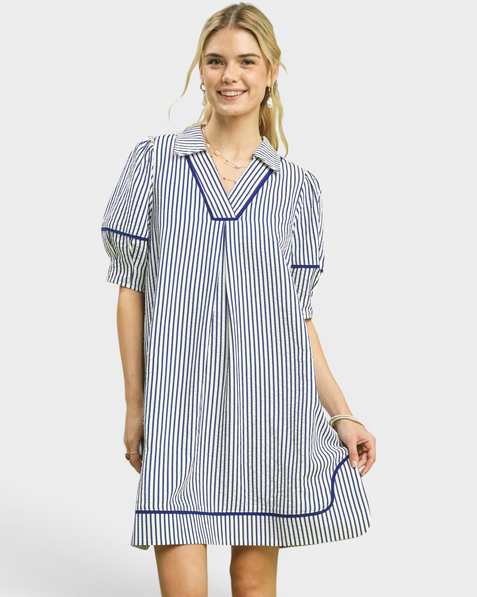 Woman wearing a blue and white striped dress with a collar on a white background