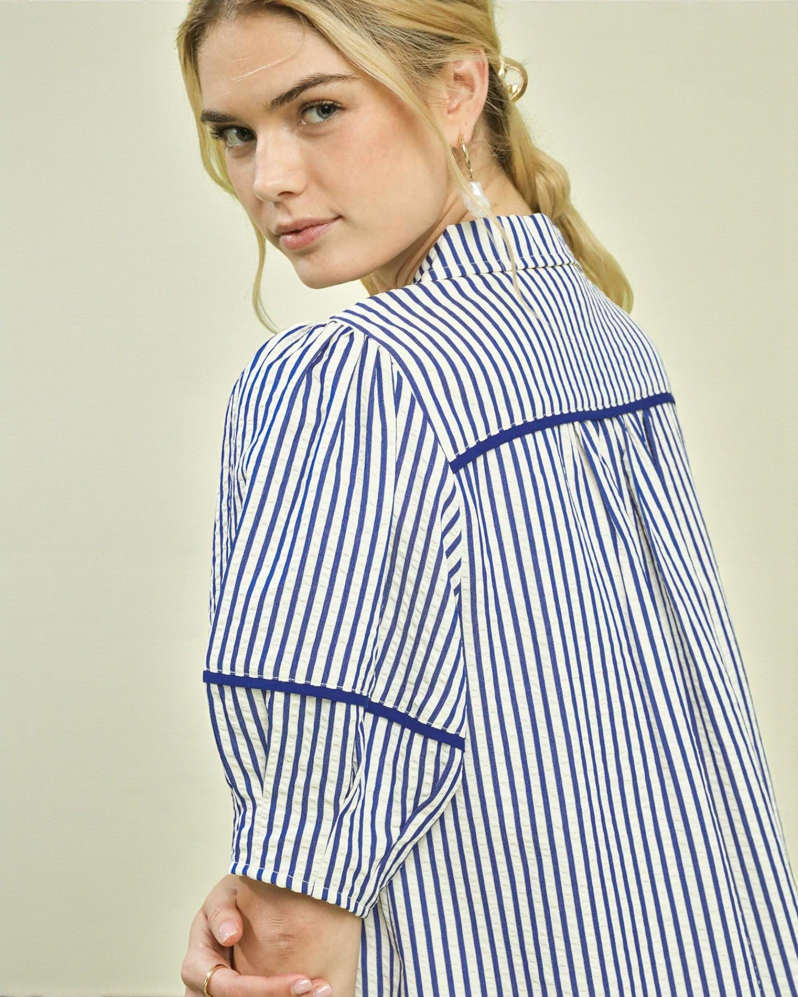 Woman wearing a blue and white striped shirt against a plain background