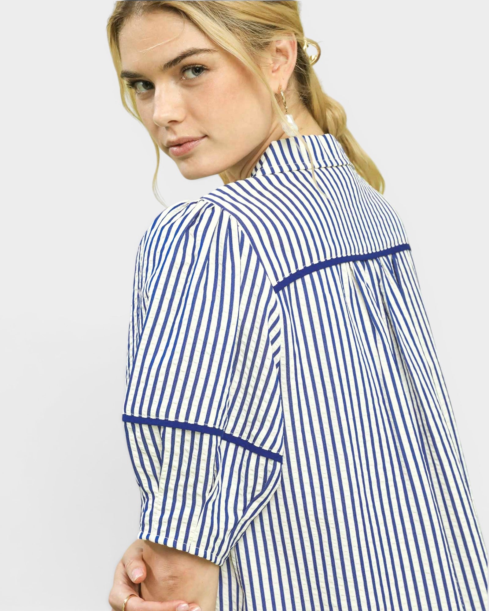 Woman wearing a blue and white striped dress on a light gray background