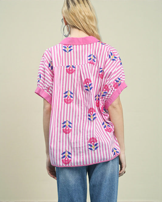 Person wearing a pink and white striped shirt with floral patterns on a beige background