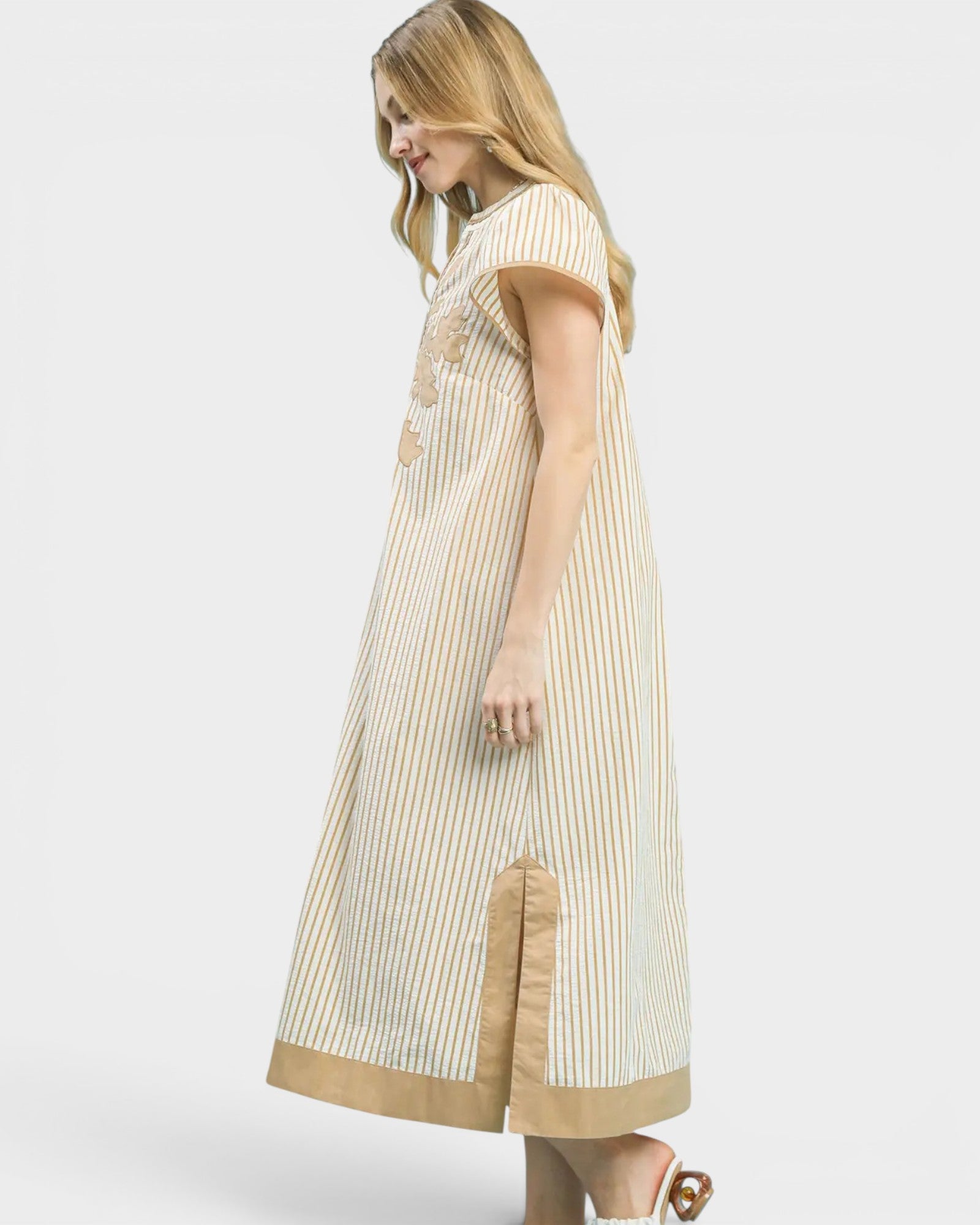 Woman wearing a beige and white striped dress on a white background