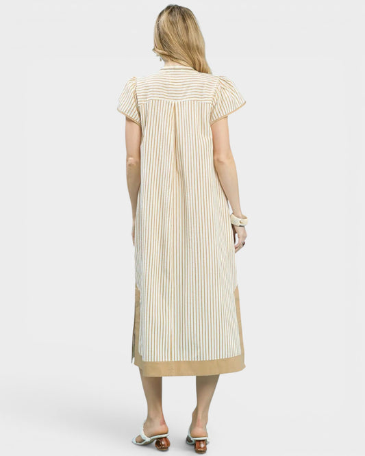 Woman wearing a cream and beige striped dress on a white background