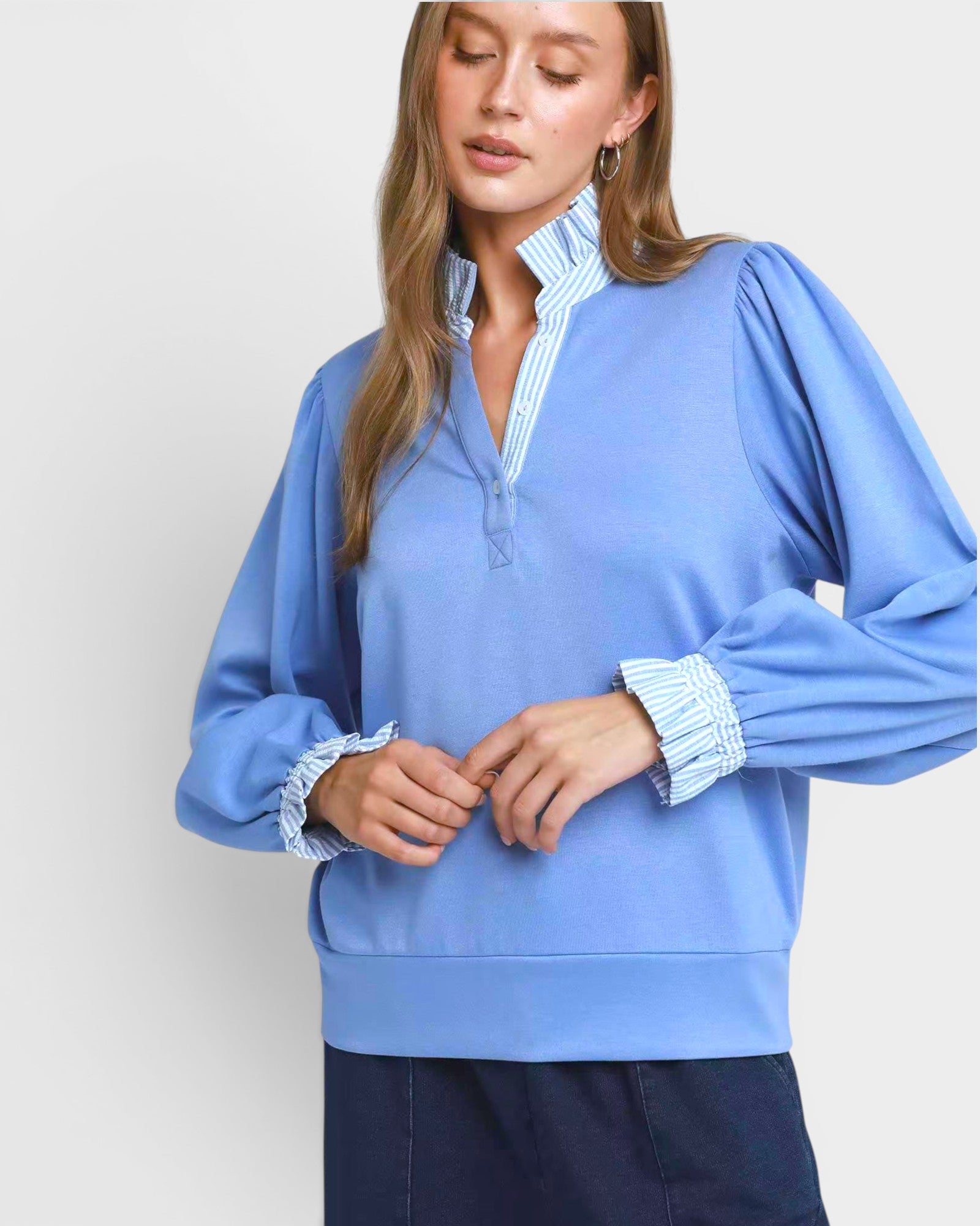 Woman wearing a blue long-sleeve shirt with a white background