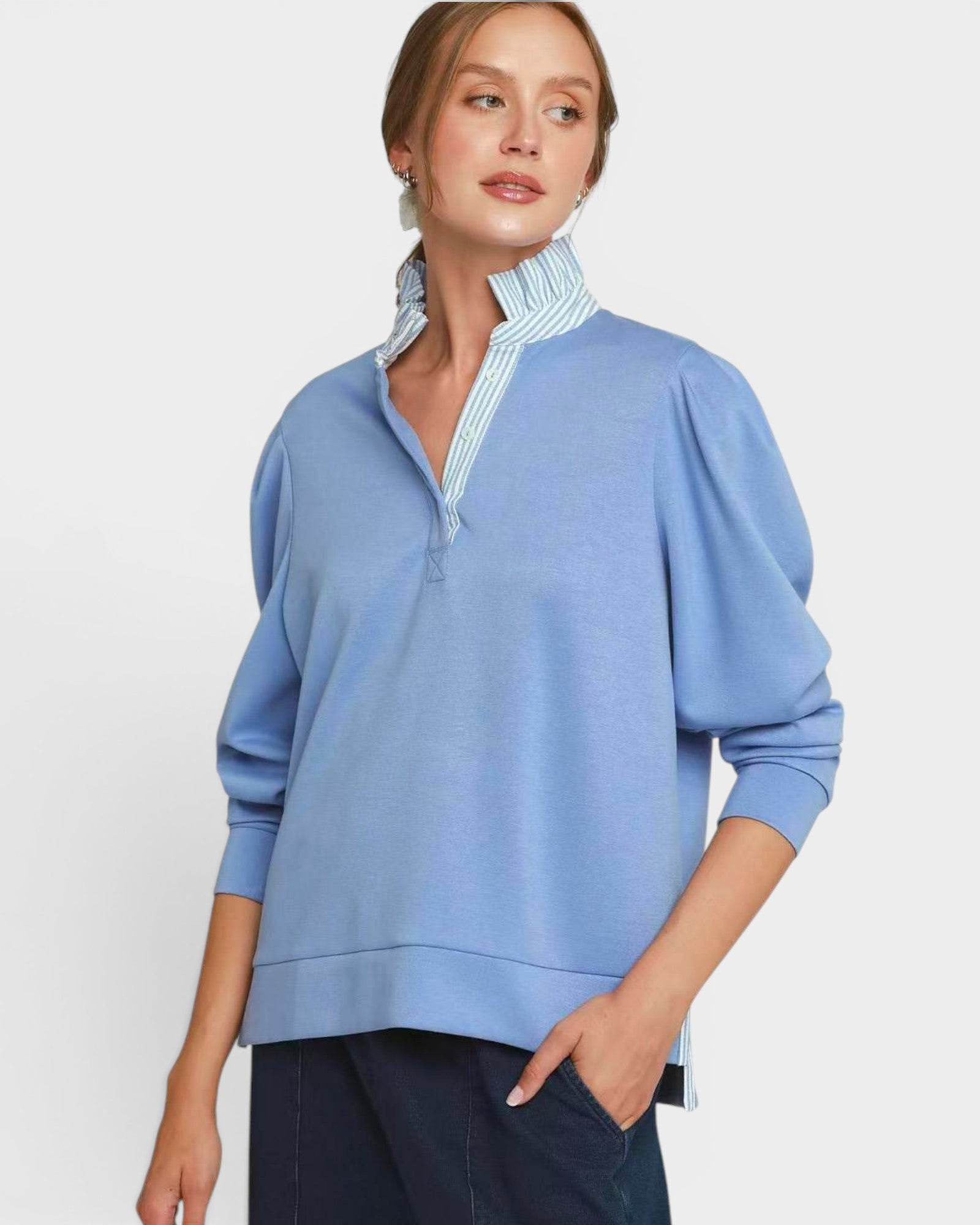 Woman wearing a light blue sweater with a striped collar against a white background