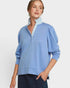 Woman wearing a light blue sweater with a striped collar against a white background